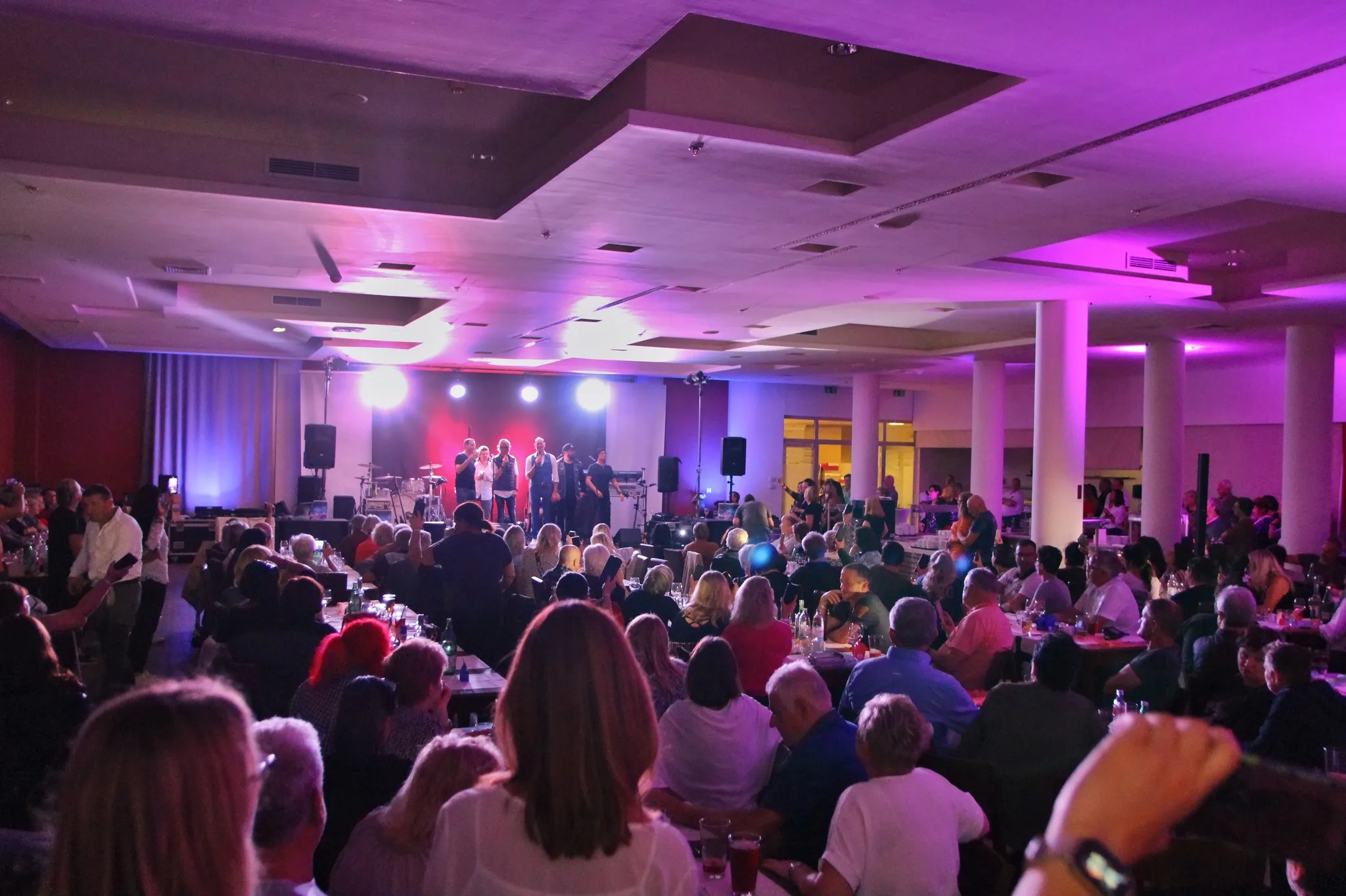 Abendprogramm der Fanreise im violett beleuchteten Saal
