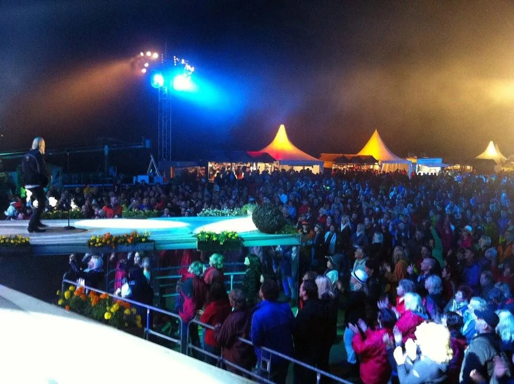 Open-Air-Bühne bei Nacht vor großem Publikum und weißen Festzelten